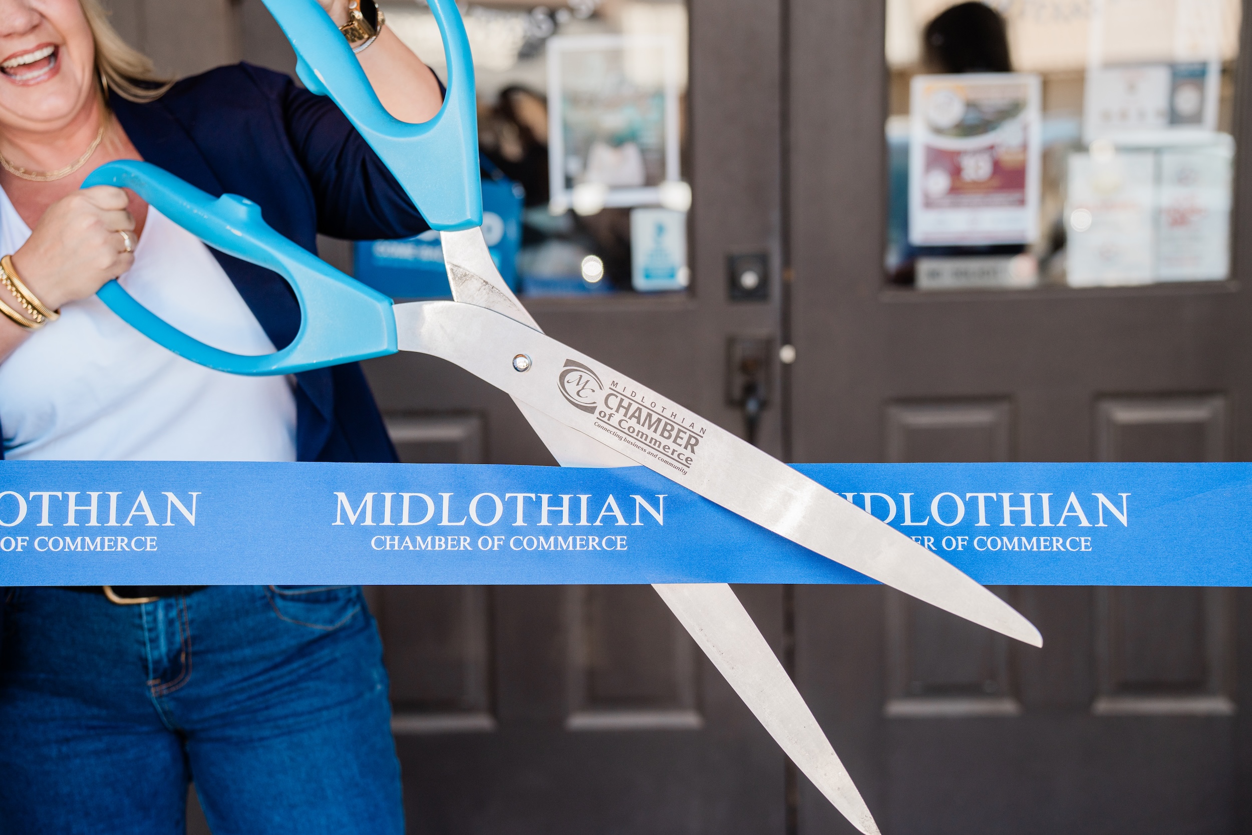 Staff member cutting ribbon in front of Midlothian Chamber of Commerce office