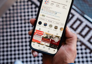 Alec Martinez holding phone showing Midlothian Chamber of Commerce Instagram profile