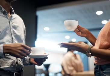 Two professionals chatting over cups of coffee