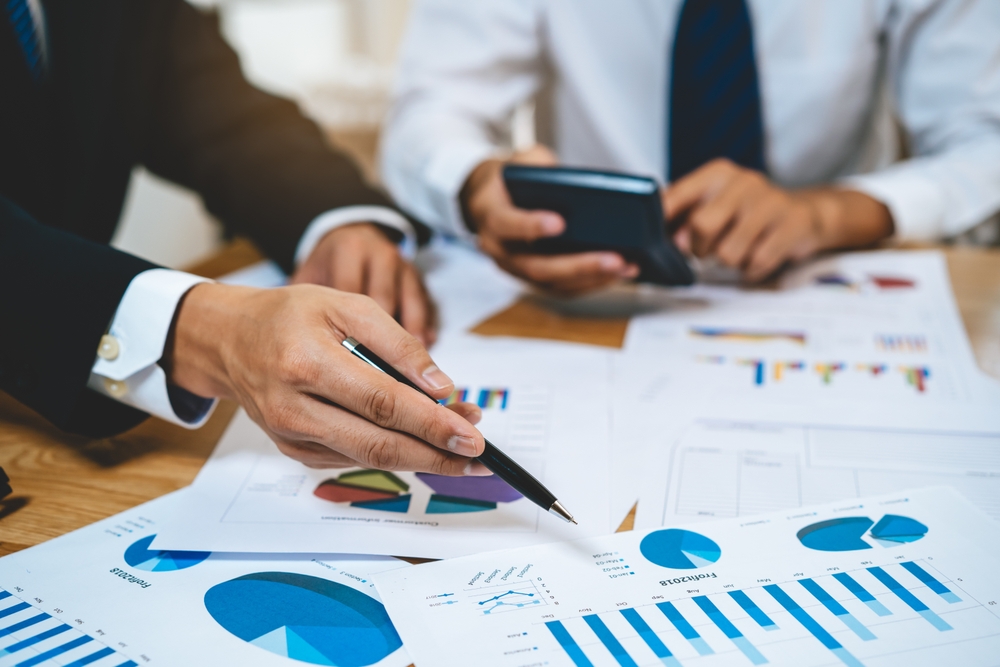Businessmen collaborating at a table with calculator and reporting